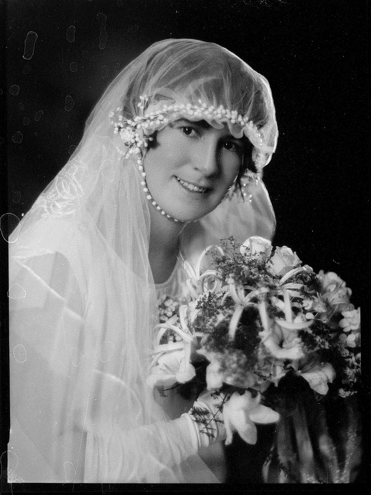 Formal archival portrait of a bride in a veil holding a bouquet